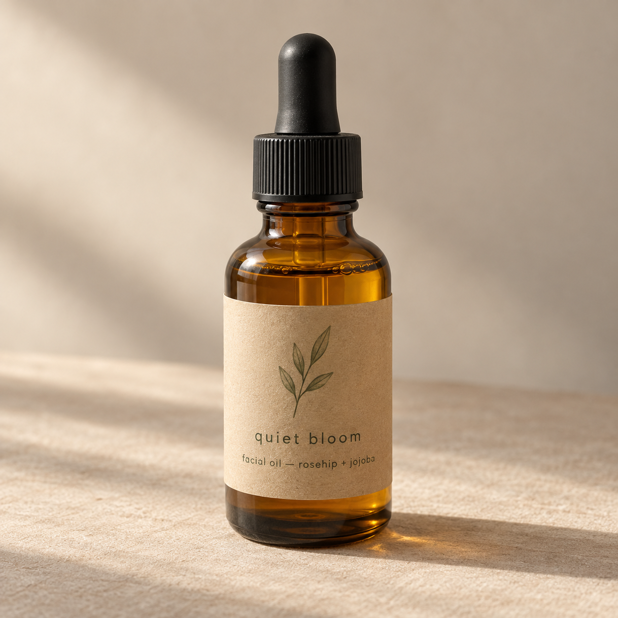Amber dropper bottle of Quiet Bloom facial oil with a kraft paper label, in soft window light.